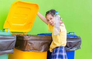 Children rubbish for recycling, Little girl throw away an empty bottle into the trash, Kids segregating trash, children and recycling photo