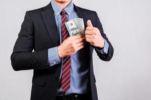 Businessman in suit holding several 100 dollar bills. Finance concept. photo