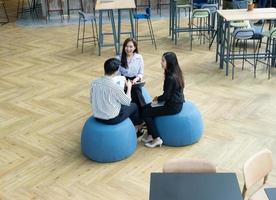 grupo de jóvenes equipos de negocios discuten algo mientras se sientan juntos en la mesa del espacio de trabajo conjunto, planifican la estrategia y la lluvia de ideas, los colegas piensan en el concepto foto
