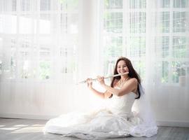 A charming female flutist performs on her instrument. A young and elegant Asian woman plays the flute