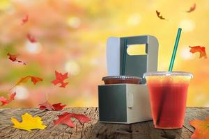 Tasty espresso and take-out coffee, cups in holder,  coffee cups in holder and paper bag on the old wood floor, and autumn maple leaves are on a wooden table photo