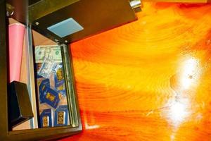 Open treasure chest filled with fine gold and Bank note dollar... on wooden table background. photo