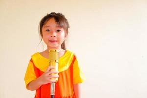 la encantadora niña viste un traje de gokowa o mugunghwa de color amarillo anaranjado, y sostiene música de canto con un micrófono dorado. vestido de moda para niñas y adolescentes. foto