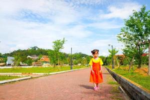 una encantadora niña viste un traje de gokowa amarillo-naranja, mugunghwa en un parque público. vestido de moda para niñas y adolescentes. foto