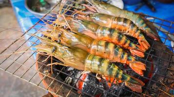 Fresh large river prawn grilled on flaming grill using charcoal stove. photo