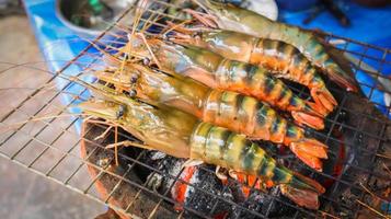 gambas de río grandes y frescas a la parrilla en llamas usando una estufa de carbón. foto