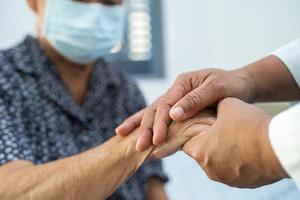 Tomados de la mano anciana asiática o anciana paciente con amor, cuidado, ánimo y empatía en la sala del hospital de enfermería, concepto médico fuerte y saludable foto