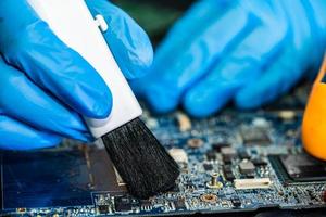 Technician use brush and air blower ball to clean dust in circuit board computer. Repair upgrade and maintenance technology. photo