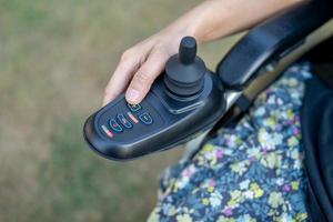 mujer asiática paciente en silla de ruedas eléctrica con joystick en la sala del hospital de enfermería, concepto médico fuerte y saludable foto