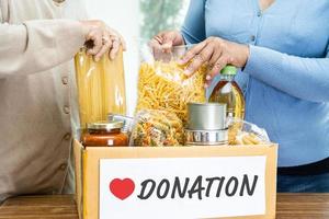 Volunteers putting various dry food in donation box for help people. photo