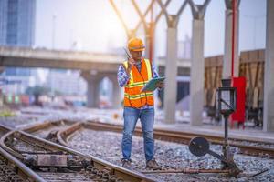 Engineer railway under  checking construction process train testing and checking railway work on railroad station with radio communication .Engineer wearing safety uniform and safety helmet in work.