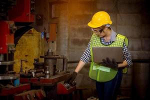 ingeniería industrial y trabajo en equipo con control uniforme de seguridad que opera la máquina rectificadora de torno que trabaja en la fábrica de la industria. foto