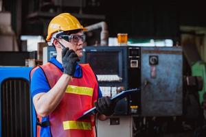 ingeniería industrial y trabajo en equipo con control uniforme de seguridad que opera la máquina rectificadora de torno que trabaja en la fábrica de la industria. foto