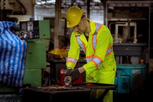 ingeniería industrial y trabajo en equipo con control uniforme de seguridad que opera la máquina rectificadora de torno que trabaja en la fábrica de la industria. foto