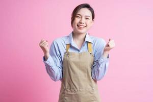 Young Asian waitress standing on pink background photo