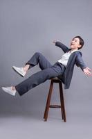 Young Asian businesswoman sitting on chair and posing on gray background photo