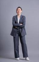 Young Asian business woman standing on gray background photo