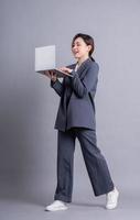 Young Asian business woman standing on gray background photo