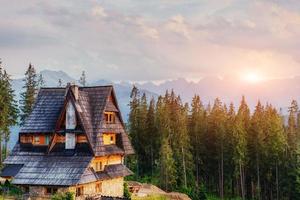 Traditional wooden house in the mountains on a green field Mount photo