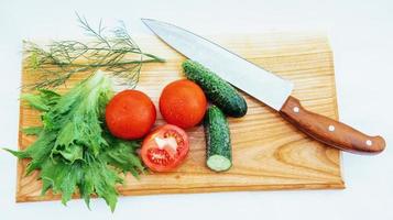 Sliced tomatoes and cucumbers on board photo