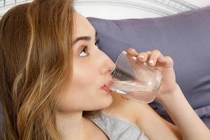 Girl woman drink water in bed at home, healthcare concept, hangover photo