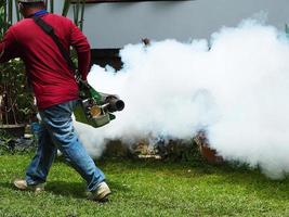 joven trabajador está trabajando empañando para eliminar los mosquitos foto