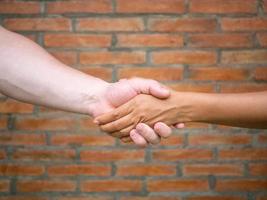 Close-up of shaking hands between man and woman with brick background photo