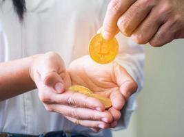 A man's hand picked up a gold bitcoin coin from a woman's palm photo