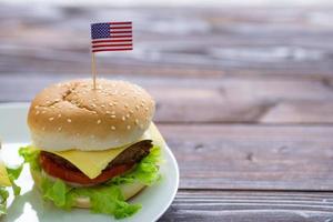 Hamburger on wooden table with American flag pin