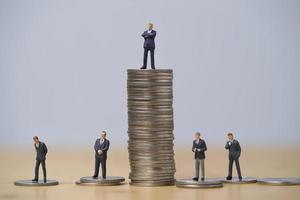 Miniature figure of five businessmen standing to different high and low coins stacking for position and successful business investment income concept. photo