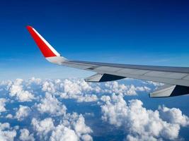 vista desde las ventanas del avión del pasajero, hermoso grupo de nubes y cielo azul. ala de avión en altitud durante el vuelo. concepto de viaje y viaje de negocios. concepto de viaje. foto