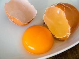 Chicken eggs cracked in white dish. photo