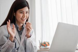 Asian woman doctor is online visiting with a patient on the internet application and Listening of the symptoms and explains how to treat the initial disease, Concept of Medical technology. photo