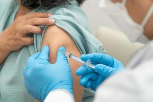 Doctors wear medical masks and vaccinated to senior women patients for the prevention of coronavirus and flu. Concept of immunization from inoculation photo