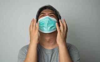 Sick Asian man wearing a medical face mask and Shoulder pain and stress. Concept of protection pandemic coronavirus and respiratory disease photo