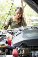 mujer asiática enojada y usando un teléfono móvil pidiendo ayuda después de una avería en el coche en la calle. concepto de problema del motor del vehículo o accidente y ayuda de emergencia de un mecánico profesional foto