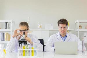 concept of a healthcare researcher, a researcher working in a life science lab, a young research scientist and a male supervisor preparing and analyzing microscopic slides in a research laboratory photo