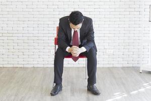 un hombre asiático con traje, sentado, tomado de la mano, calma tu mente en la silla foto