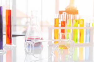 Clear plastic glasses, test tubes in a stand and a microscope on a white table for science research photo