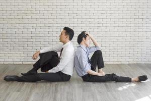 Two male employees sat on the floor showing signs of stress from overwork. photo