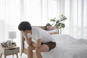 An Asian gay man sitting in bed after an argument with his boyfriend with the idea of an LGBT couple. photo