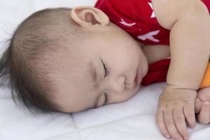 An Asian baby is sleeping in the bed. photo