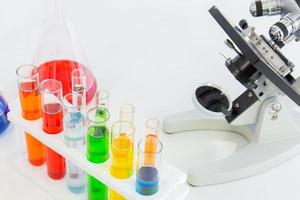 Test tubes in a stand and a microscope on a white table photo