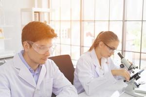 concept of a healthcare researcher, a researcher working in a life science lab, a young research scientist and a male supervisor preparing and analyzing microscopic slides in a research laboratory photo
