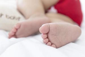 The baby's feet are sleeping in the bed. photo