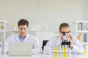 concept of a healthcare researcher, a researcher working in a life science lab, a young research scientist and a male supervisor preparing and analyzing microscopic slides in a research laboratory photo
