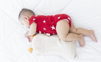 An Asian baby is sleeping in the bed. photo