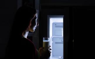 una mujer embarazada que se despierta tarde en la noche buscando comida en el refrigerador foto