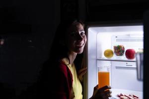 una mujer embarazada que se despierta tarde en la noche buscando comida en el refrigerador foto