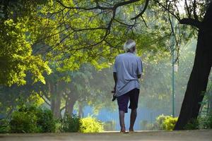 Old man goes alone through the park photo